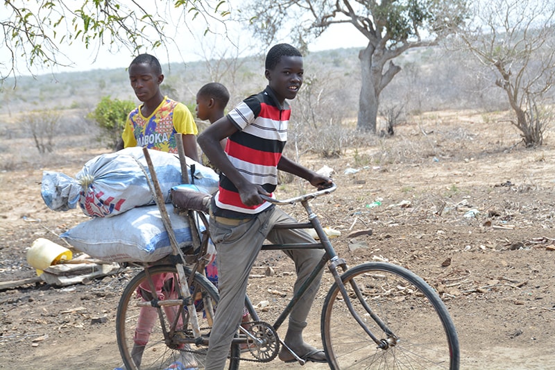 写真：自転車に積み荷を載せて走っていく少年